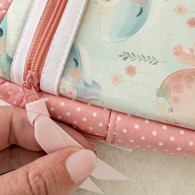 Mochila de tecido rosa com padrão de bolinhas e ilustração de golfinhos azuis e flores