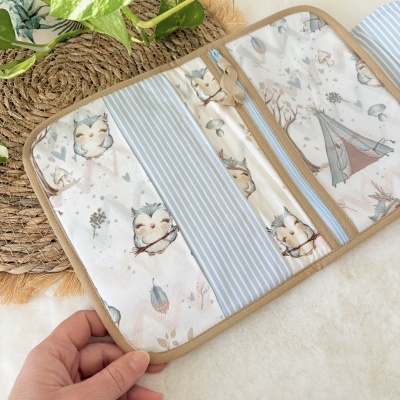 Organizador tecido azul com padrão de corujas e riscas, fecho de correr azul e borda bege.