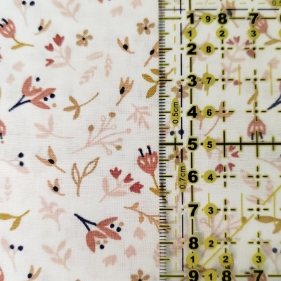 tecido branco com padrão floral delicado e régua transparente com marcações em cm