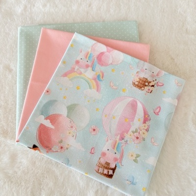 Três tecidos dobrados com padrões infantis e cores suaves