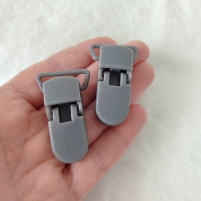 Dois clips de plástico cinza na mão