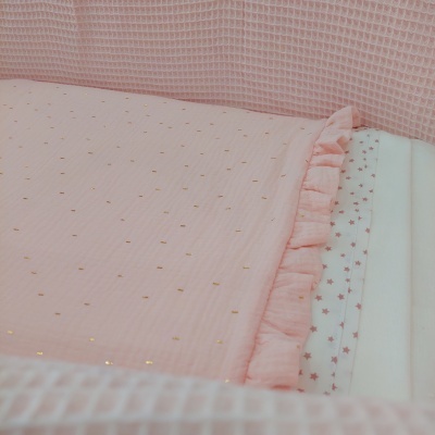 Manta rosa clara com pontos dourados e folho em cama com lençol branco estampado com estrelas cor-de-rosa