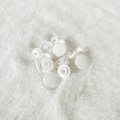 Botões de pressão brancos em plástico sobre tecido peludo branco