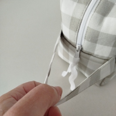 Mochila xadrez beje e branco com fecho de correr branco e cordão cinzento