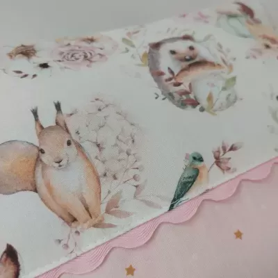Tecido com ilustrações de animais e flores em tons pastel e tecido rosa com estrelas douradas.