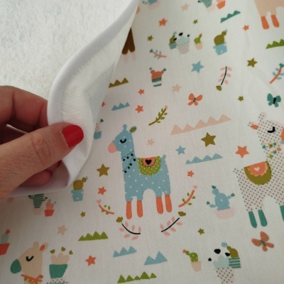 Fralda de tecido estampada com girafas e estrelas em várias cores pastel.