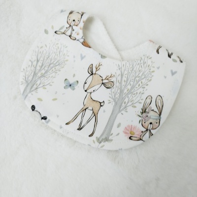 Babete branco com padrão de animais e árvores para bebé