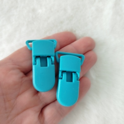 Dois clips de plástico azul turquesa na mão