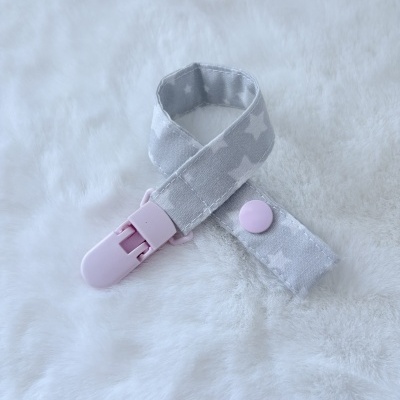 Prendedor de tecido com clip rosa sobre tecido branco macio.