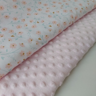 Tecidos sobrepostos com padrão floral branco e rosa e textura de bolinhas rosa claro.