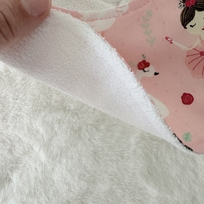 Babete de tecido com padrão de bailarinas e cisnes em fundo rosa