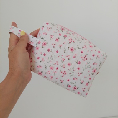 Bolsa de tecido branca com flores rosas segurada por mão com unhas amarelas