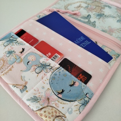 Carteira rosa claro com padrão de estrelas e ilustrações de animais sorridentes com olhos fechados e passaporte azul