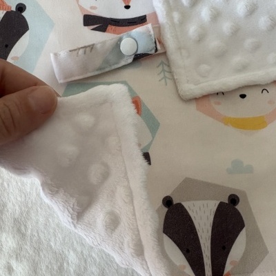 Manta branca macia com bolinhas e estampas de animais sobre tecido branco