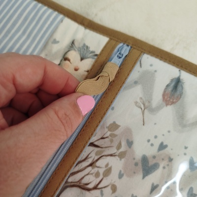 Estojo com padrão de corujas e árvores em tecido bege e azul com fecho de correr e detalhes castanhos.