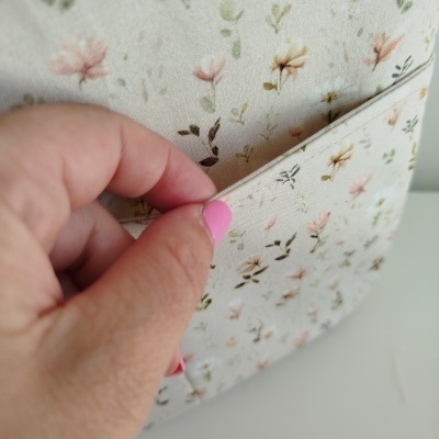 Tecido floral em tons pastel sendo segurado por mão feminina