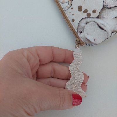 Mão segurando fita branca ondulada de estojo com padrão cinzento e castanho