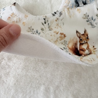 Babete branco com padrão de folhas e animais em tecido macio