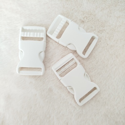 Três fivelas de plástico brancas sobre superfície macia bege.