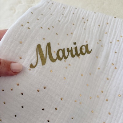 Pano branco com pontos dourados e nome Maria em dourado.