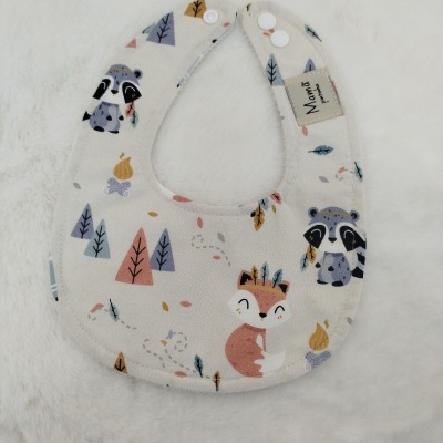 Babete para bebé com padrão de raposa e guaxinim em tecido bege