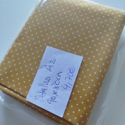 Tecido amarelo com bolinhas brancas embalado com etiqueta