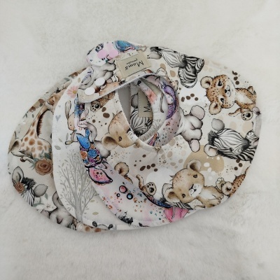 Três babetes redondos de tecido com padrão de animais infantis e botões de fecho