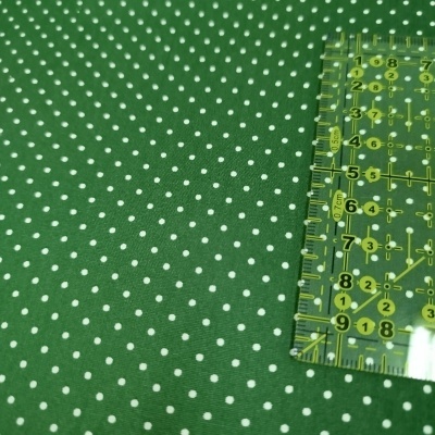 Tecido verde com bolinhas brancas e régua transparente amarela