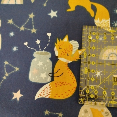 Tecido azul com padrão de raposa laranja e estrelas com régua para medir.