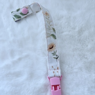 Fita floral com clip rosa sobre superfície branca macia