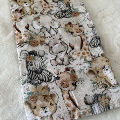 Pano tecido com padrão de animais fofos e flores sobre superfície branca peluda