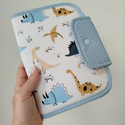 Carteira com padrão de dinossauros e fecho azul com bolinhas brancas