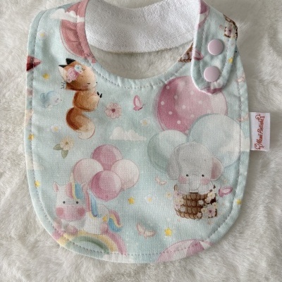 Babete de tecido para bebé com estampado de animais e balões em tons pastel