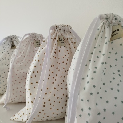 Sacolas de pano estampadas com estrelas coloridas, alinhadas sobre uma superfície