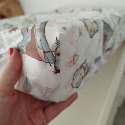 Tecido com padrão de pássaros coloridos, segurado por mão com unhas vermelhas