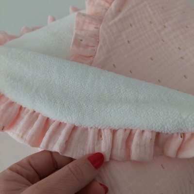 Toalha branca com borda rosa com folhos e detalhes dourados, mãos seguram a toalha