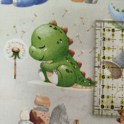 Estampa de dinossauro verde sorridente e dente-de-leão em tecido branco com régua transparente amarela