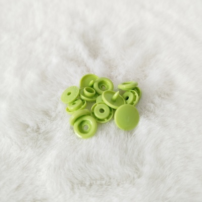 Botões de pressão plásticos verdes claros sobre tecido felpudo branco