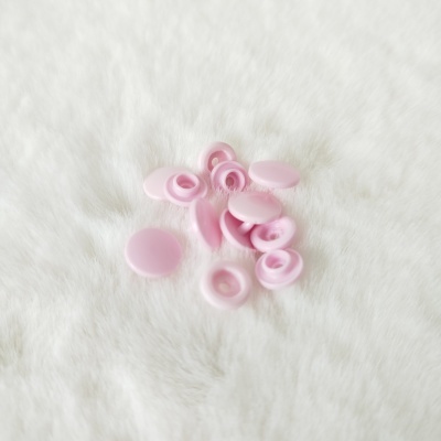 Botões de pressão rosa de plástico sobre superfície branca peluda