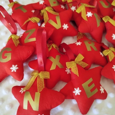 Decoração de Natal em estrelas vermelhas com laços dourados e letras douradas.