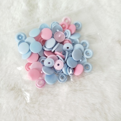 Botões de plástico rosa e azul em saco plástico sobre superfície branca macia