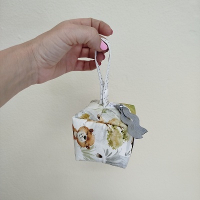 Saco de tecido pequeno com padrão de ursinho e flores, segurado por mão feminina
