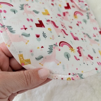 Babete de bebé com padrão de unicórnios cor-de-rosa e castelos