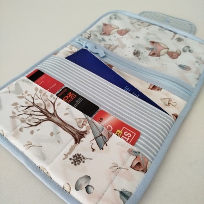 Carteira de tecido com padrão de raposas e folhas e vários bolsos contendo cartões