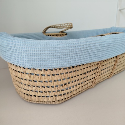 Cesto de vime com forro azul claro sobre superfície branca