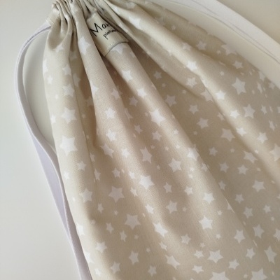 Saco de tecido bege com estrelas brancas e cordões brancos