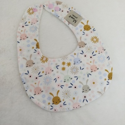 Babete de tecido com padrão de coelhos e flores sobre fundo branco