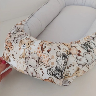 Cama para bebé com capa de padrão de animais selvagens em tons de bege e castanho.