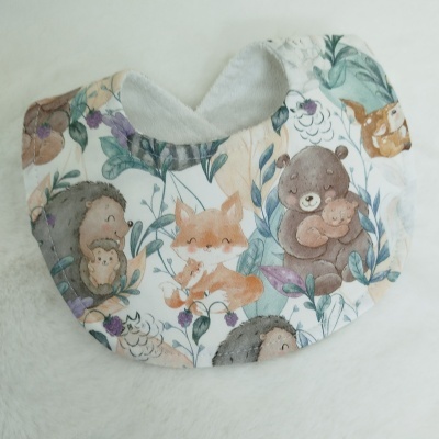 Babete de bebé com padrão de animais animados coloridos e interior branco felpudo