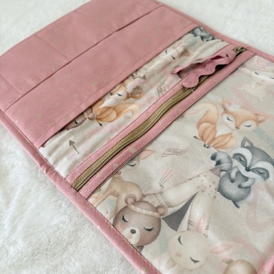 Organizador de tecido rosa com fecho e interior estampado com animais.